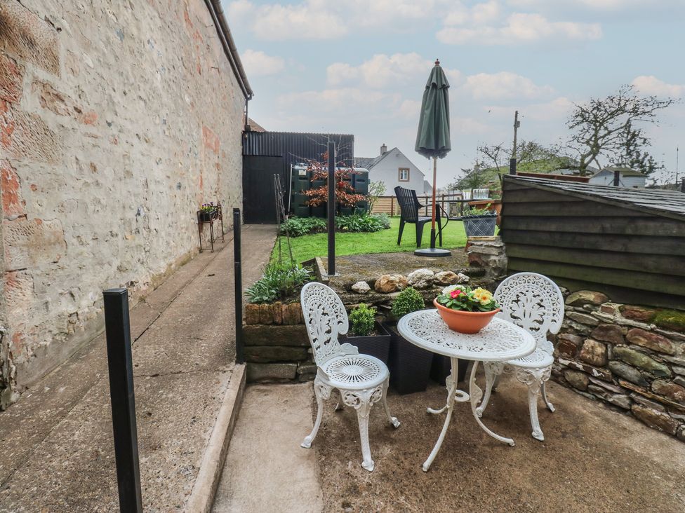 A garden with a table and chairs at 1 Brookside in Warcop
