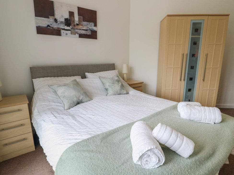 A bedroom with a bed and wardrobe at Seaview in Benllech near Red Wharf Bay