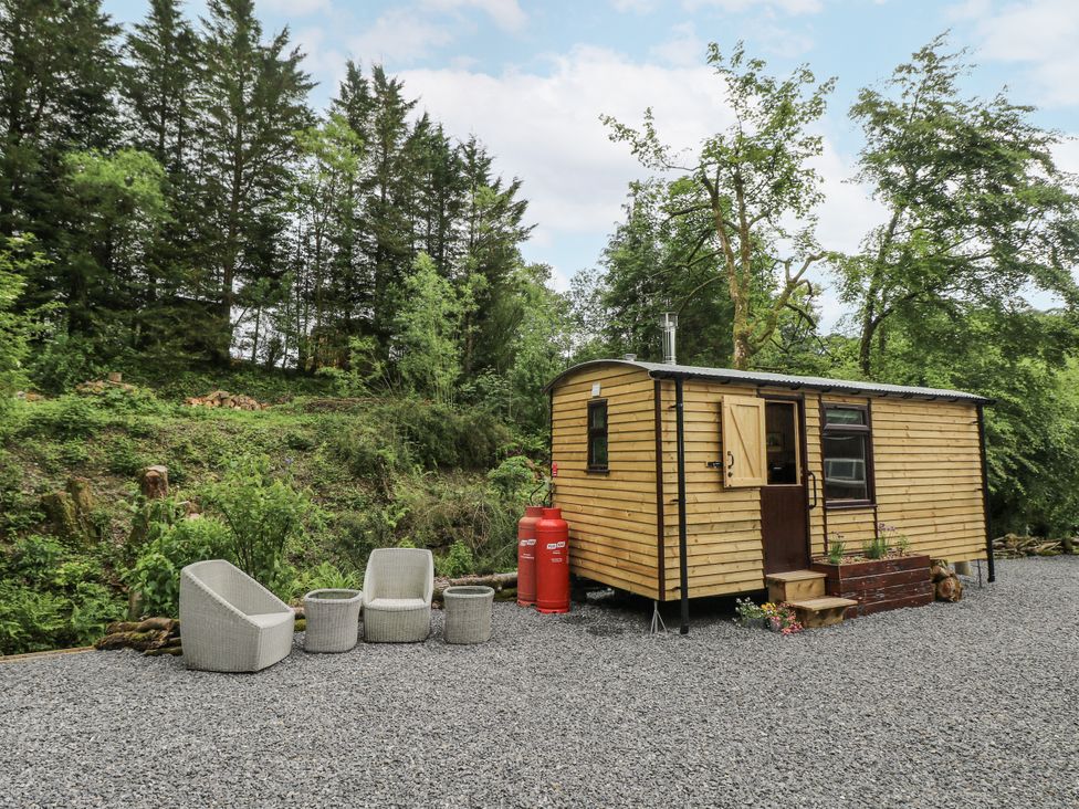 A wooden cabin with outdoor seating and gas canisters at The Hamper in Felingwm near Carmarthen