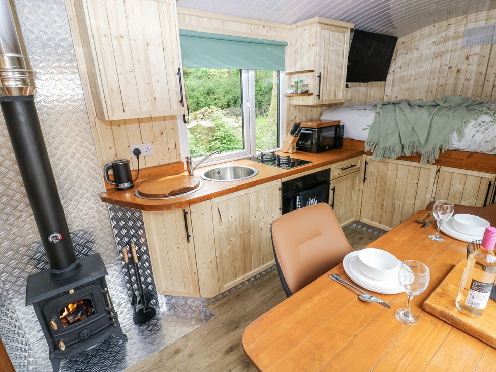 A kitchen with wooden cabinets and a dining table at The Hamper in Felingwm near Carmarthen