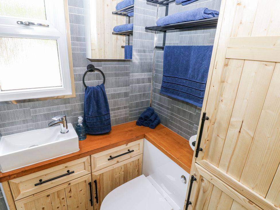 A bathroom with a sink, towel rack, and toilet at The Hamper in Felingwm near Carmarthen