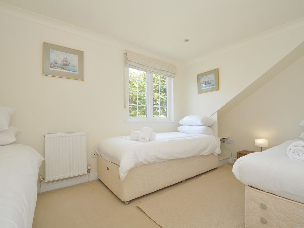 A bedroom with three beds and a window at Bodare 8 in Daymer Bay