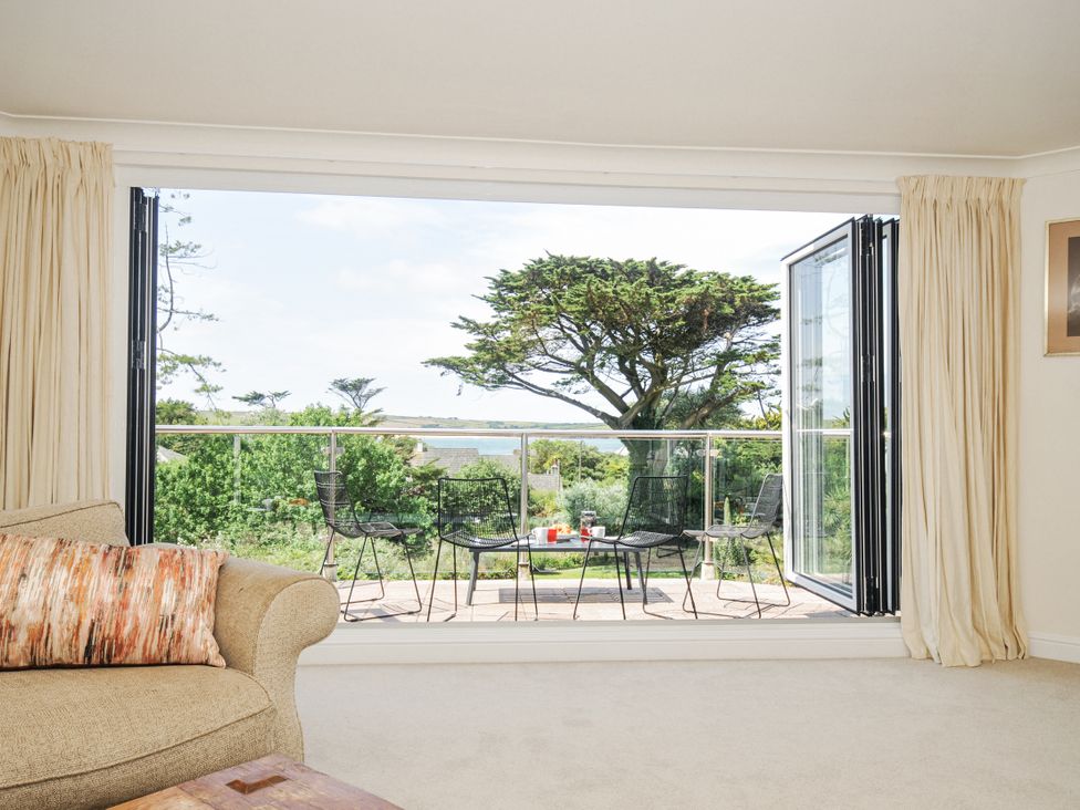 A living room with a view of the balcony and garden at Bodare 8 in Daymer Bay