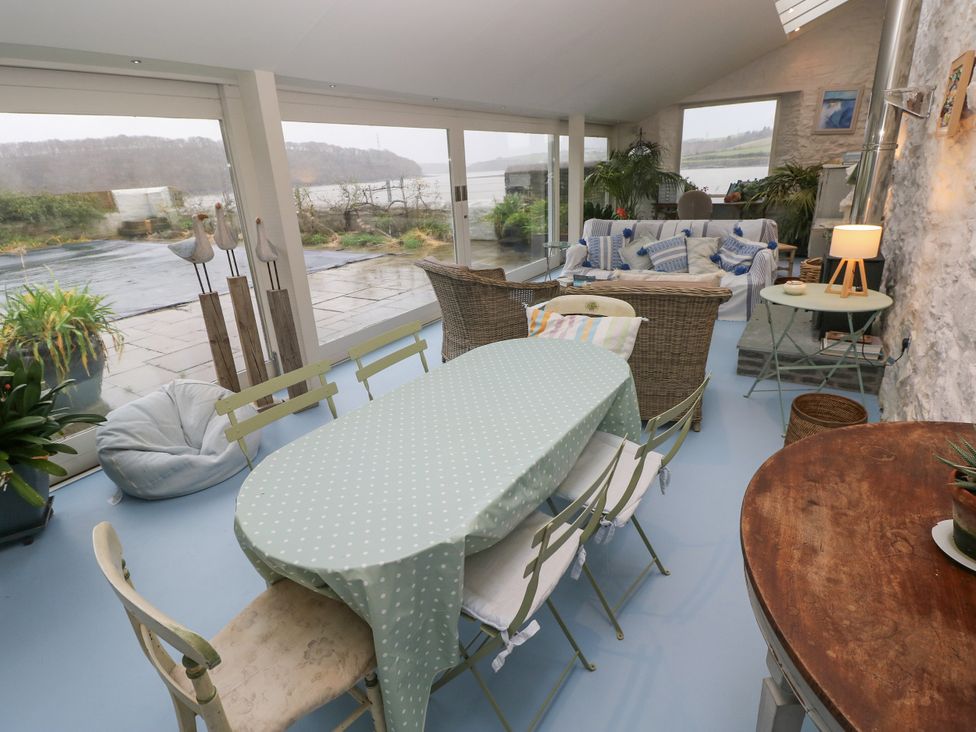 A conservatory with a table and chairs at Curlew House in Cosheston