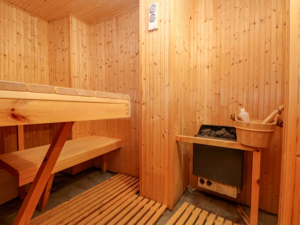 A sauna with wooden benches and a wood stove at Curlew House in Cosheston