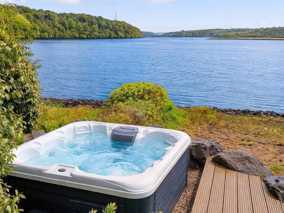 A hot tub next to water at Curlew House in Cosheston