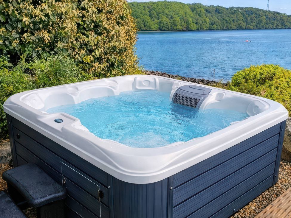 A hot tub by the water in the garden at Curlew House Cosheston