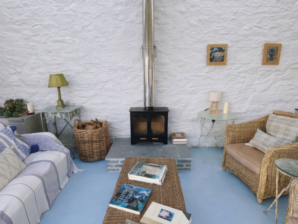 A snug with a wood stove and seating at Curlew House in Cosheston