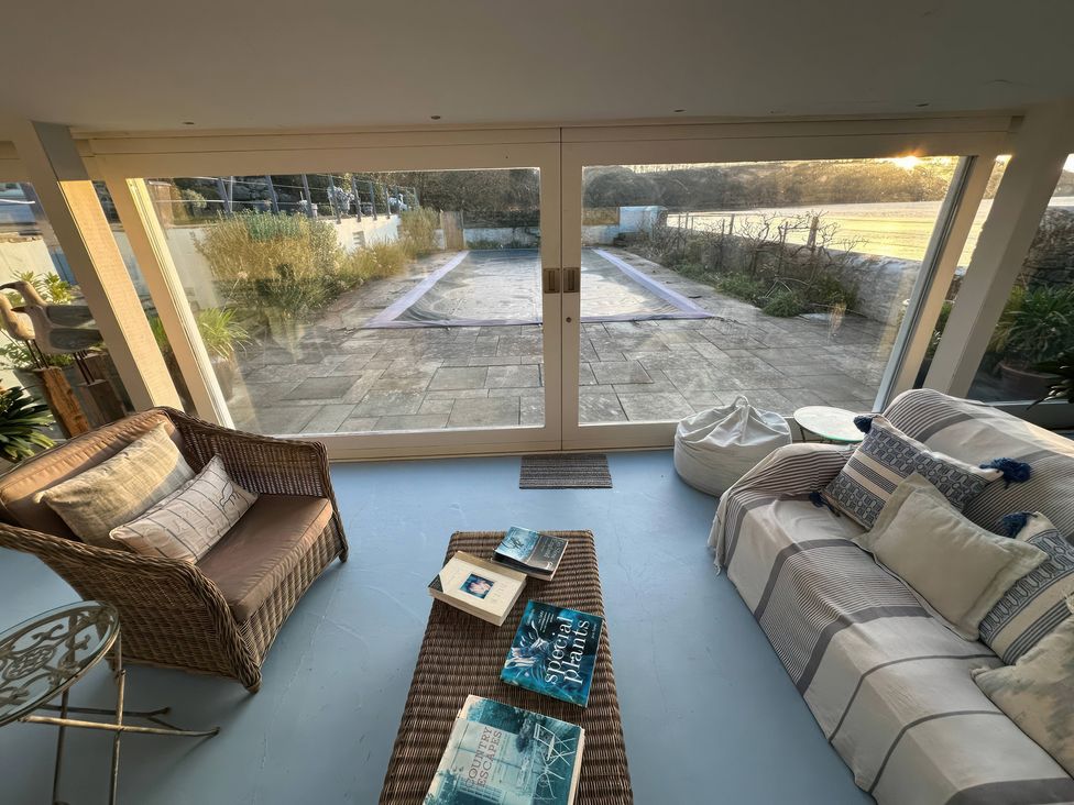 A conservatory with seating and a view of the patio at Curlew House in Cosheston