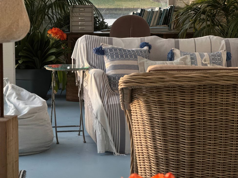 A snug with a sofa and cushions at Curlew House in Cosheston