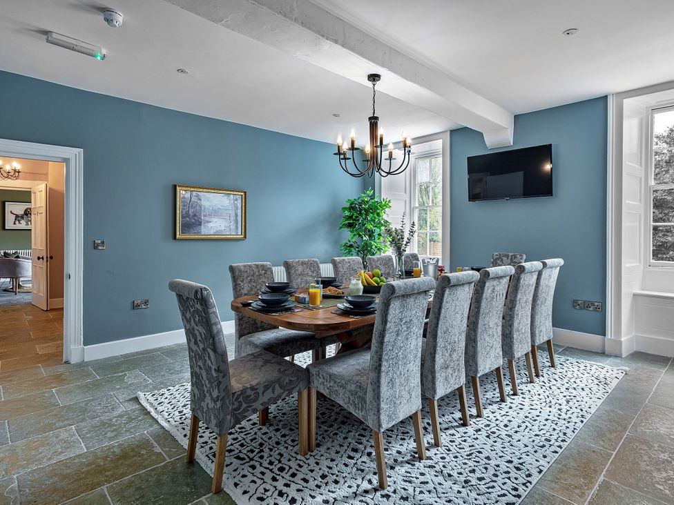 A dining room with a long table and chairs at Snowdonia Manor in Dolgellau