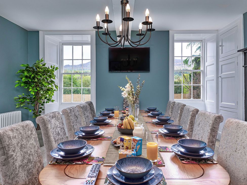 A dining room with a long table and chairs at Snowdonia Manor in Dolgellau