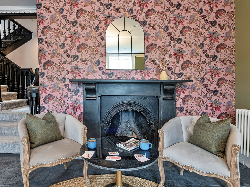 A living room with a fireplace, chairs, and a table at Snowdonia Manor in Dolgellau