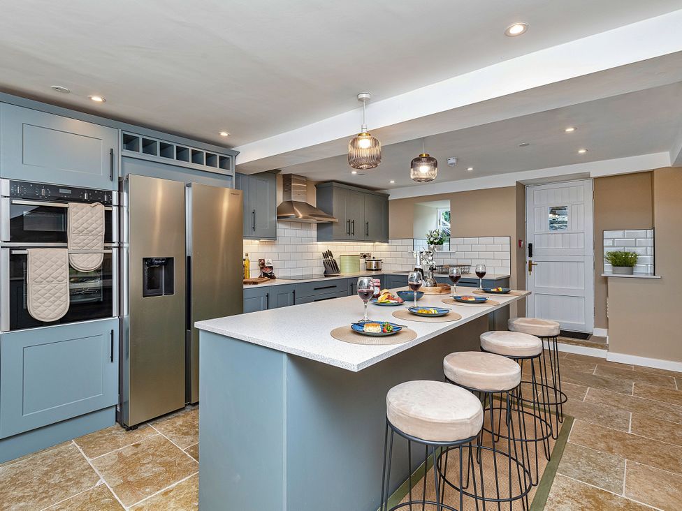 A kitchen with a countertop, refrigerator, and bar stools at Snowdonia Manor in Dolgellau