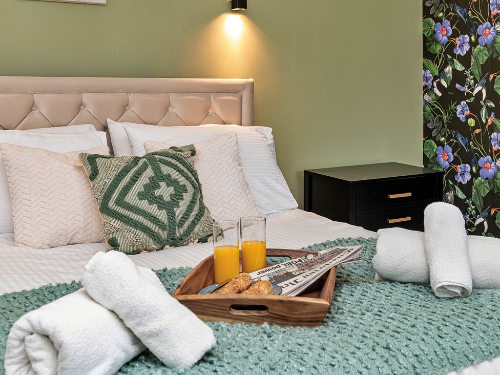 A bedroom with a bed, towels, and juice on a tray at Snowdonia Manor in Dolgellau
