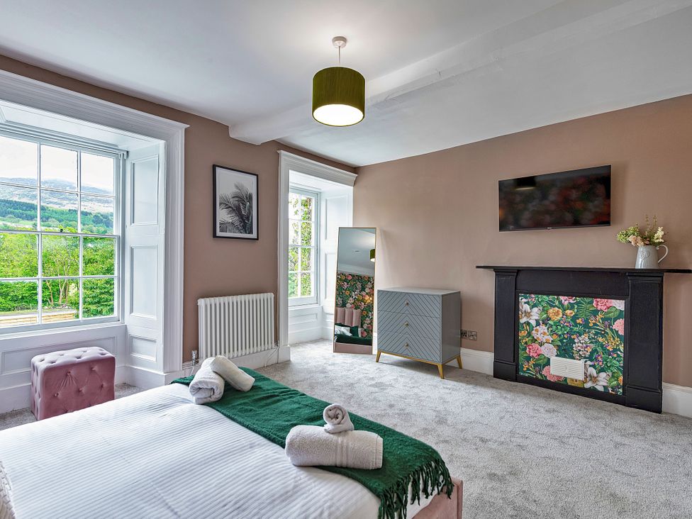 A bedroom with a window, mirror, and chest of drawers at Snowdonia Manor in Dolgellau