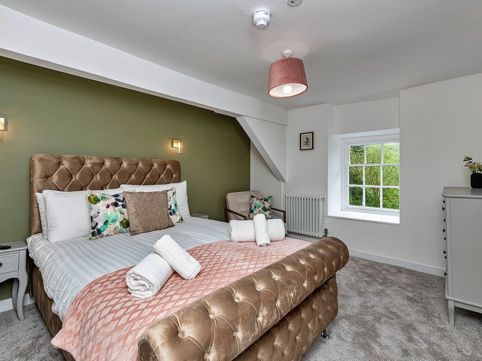 A bedroom with a bed, window, and dressing table at Snowdonia Manor in Dolgellau
