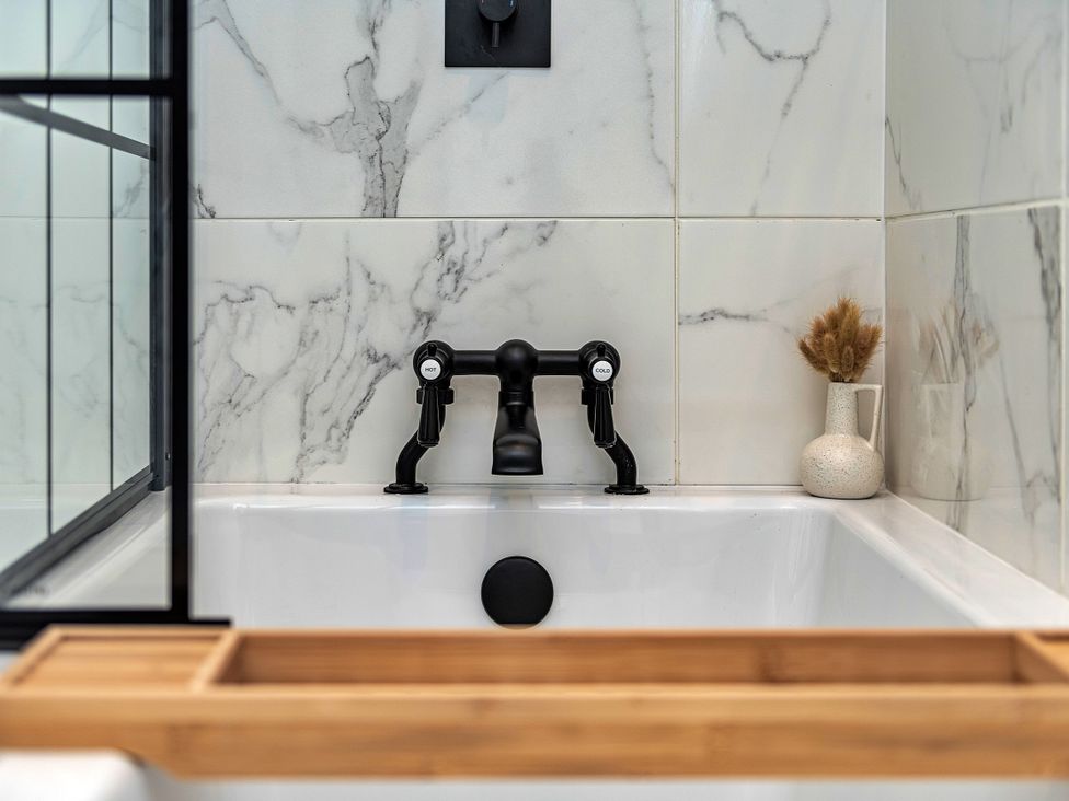 A bathtub with a black faucet and decorative vase in the bathroom at Snowdonia Manor in Dolgellau