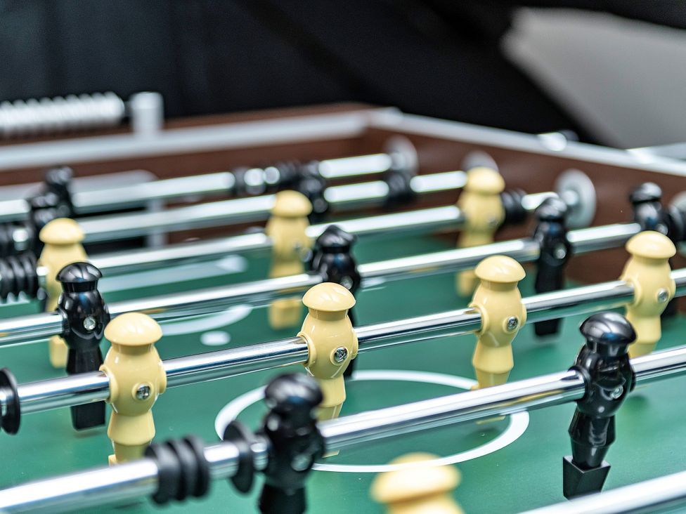 A foosball table with yellow and black player figurines in a game room at Snowdonia Manor in Dolgellau