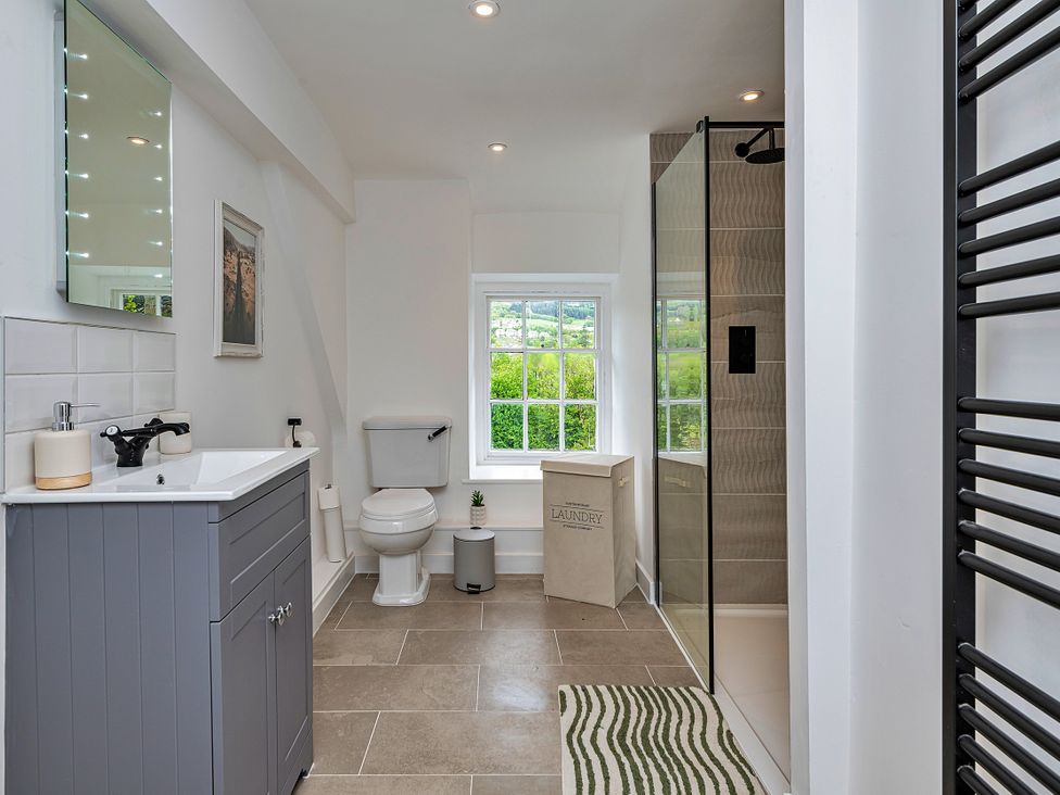 A bathroom with a sink, toilet, shower, and window at Snowdonia Manor in Dolgellau