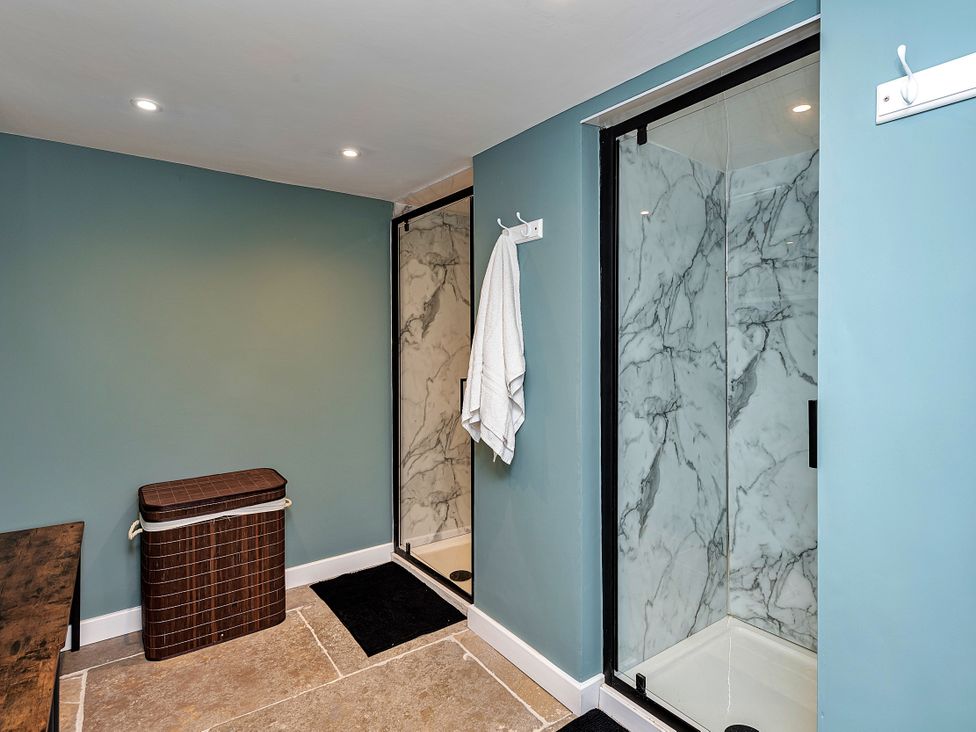 A bathroom with a shower, laundry basket and towel at Snowdonia Manor in Dolgellau