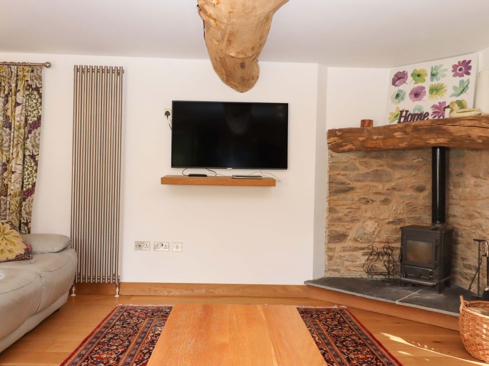 A living room featuring a sofa, television, and wood burner at Swallows Reach Halwell