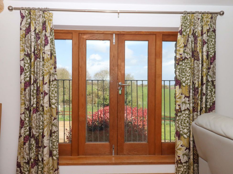 A window with curtains and garden view at Swallows Reach in Halwell
