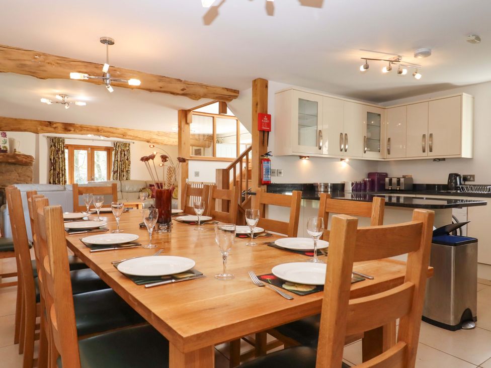 A dining area with a wooden table and kitchen cabinetry at Swallows Reach Halwell