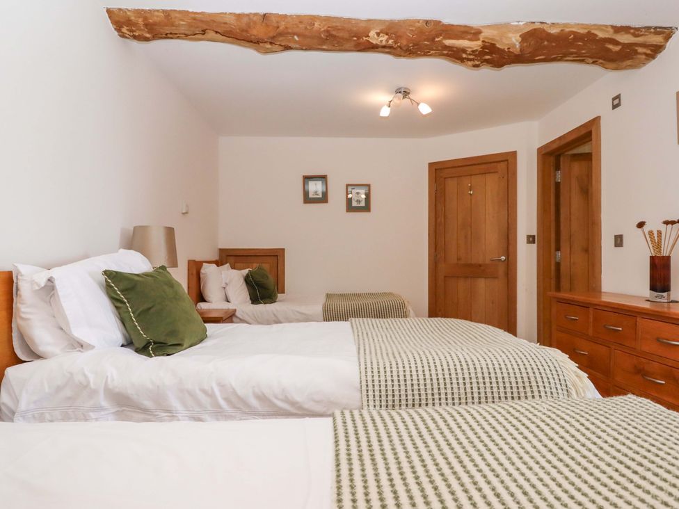 A bedroom with two beds and a wardrobe at Swallows Reach, Halwell