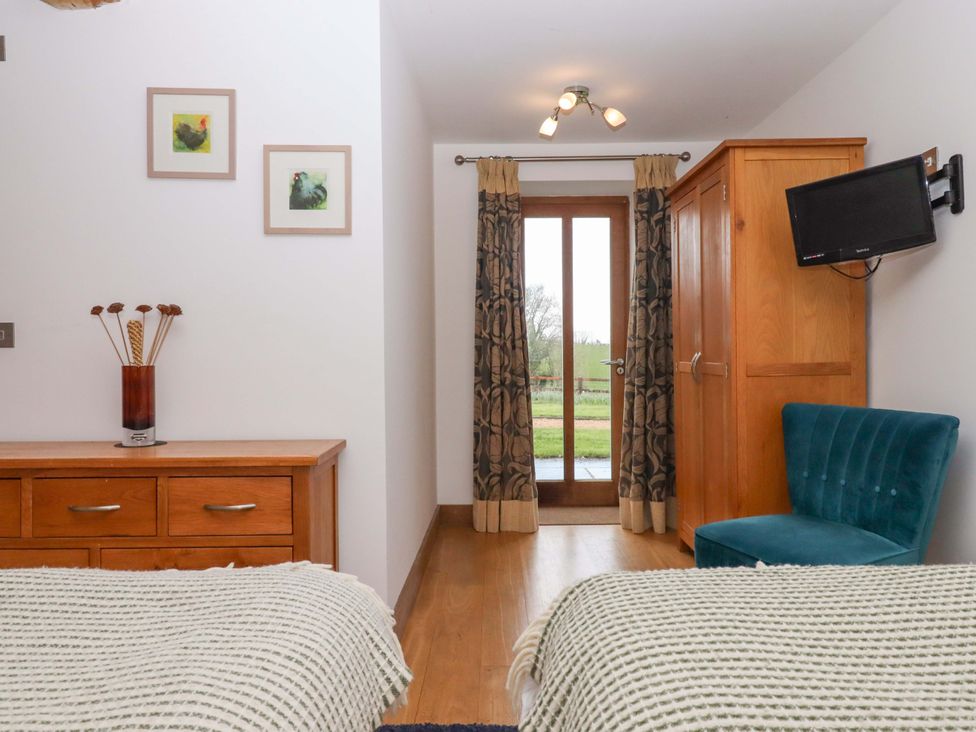 A bedroom with two beds and a wardrobe at Swallows Reach in Halwell