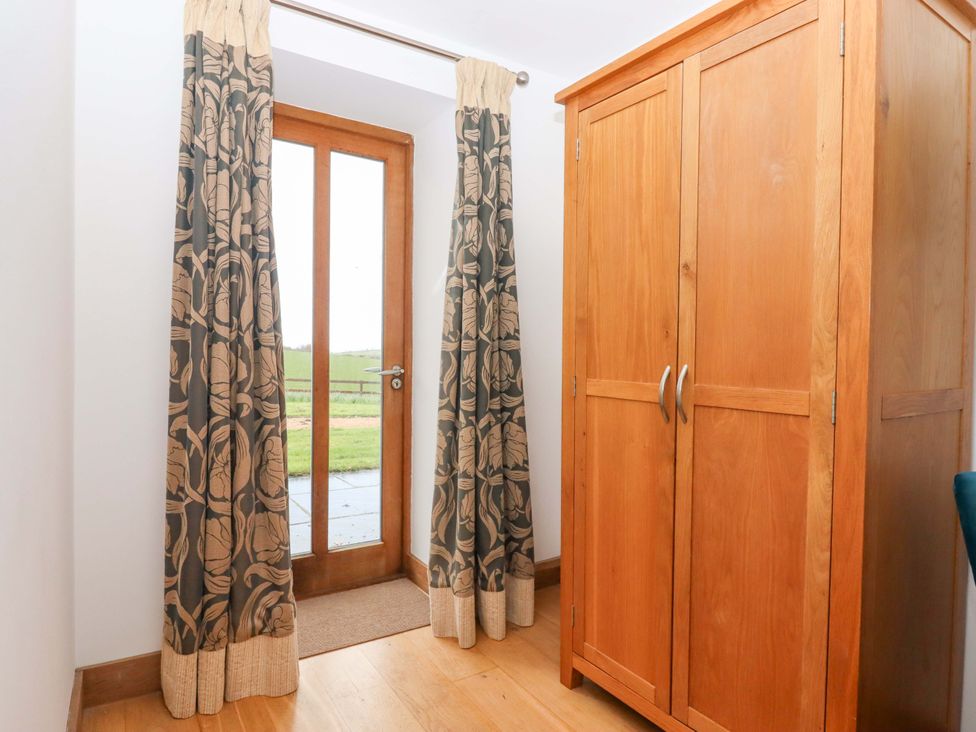 A hallway with curtains and a wooden wardrobe at Swallows Reach Halwell