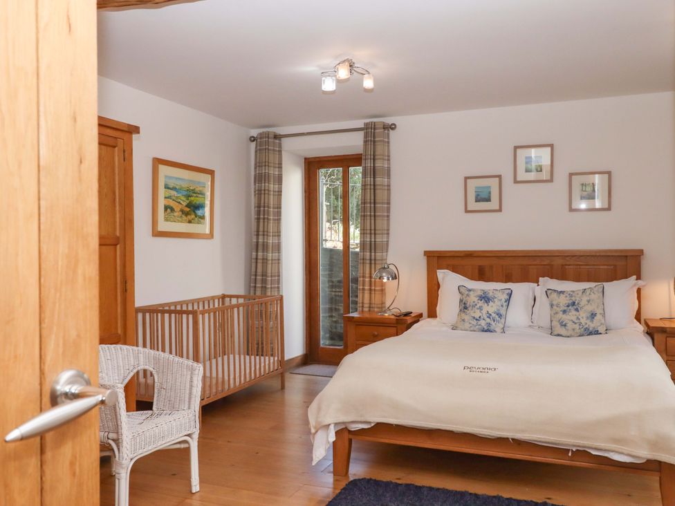 A bedroom with a bed and crib at Swallows Reach Halwell