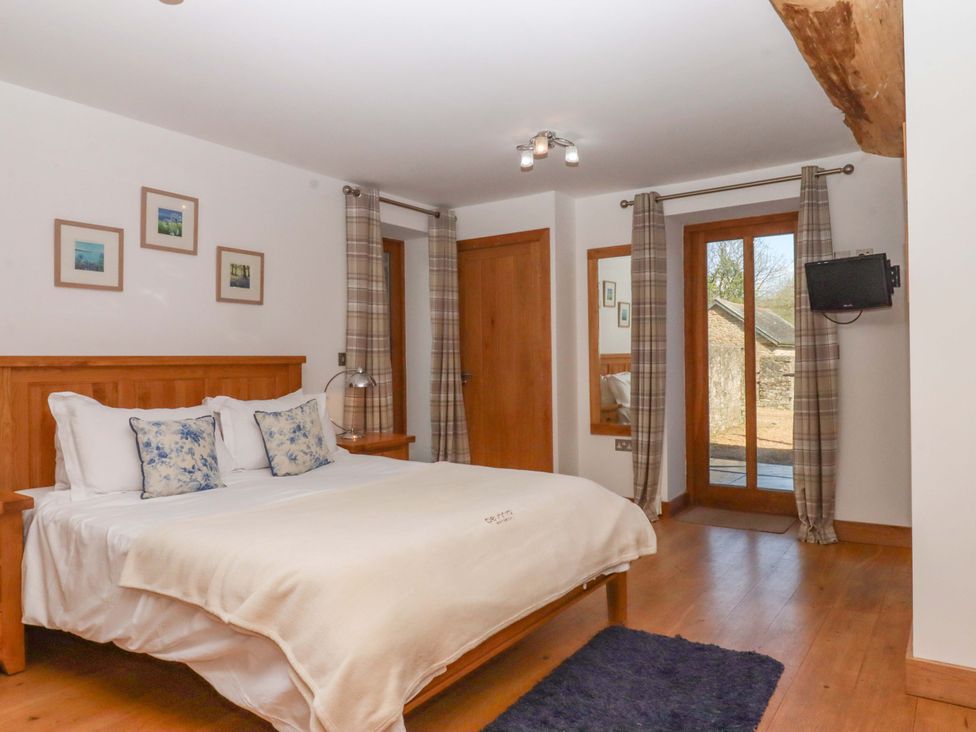 A bedroom with a bed and a door leading outside at Swallows Reach Halwell