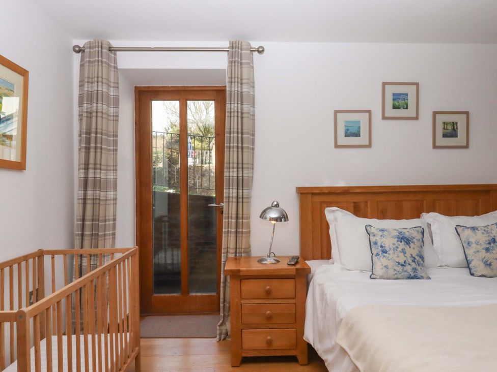 A bedroom with a crib and bed at Swallows Reach Halwell