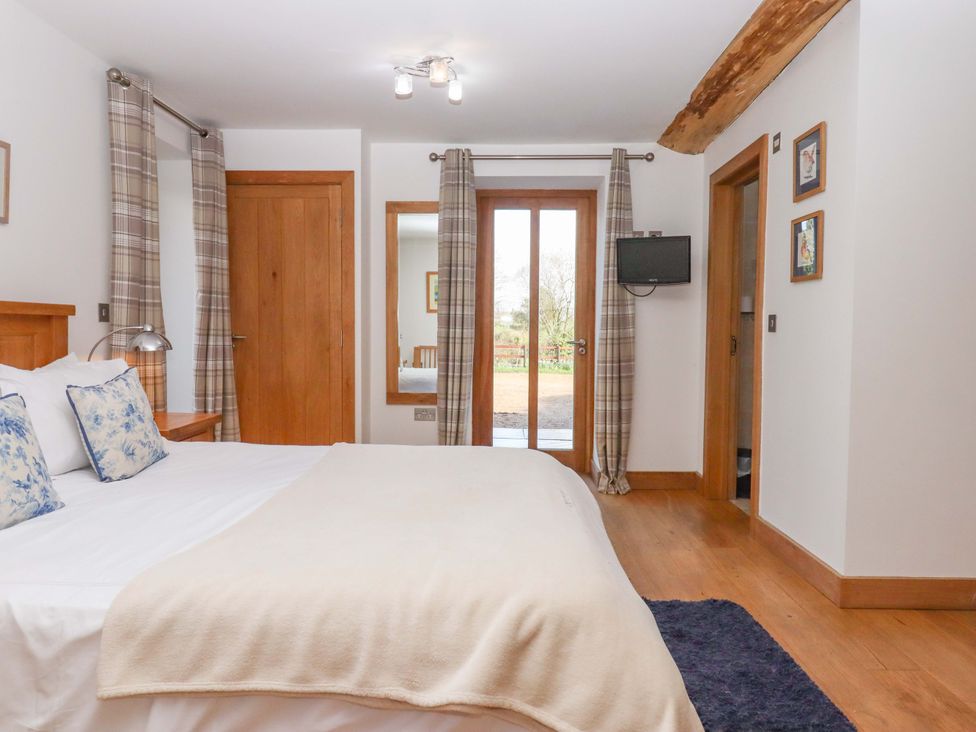 A bedroom with a bed and sliding doors at Swallows Reach Halwell