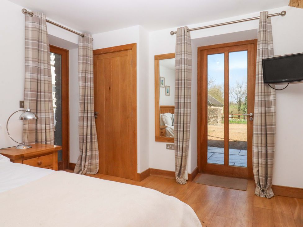 A bedroom with a bed, a lamp, and a television at Swallows Reach in Halwell