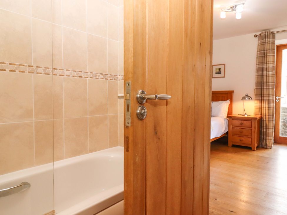 A bathroom with a bath tub visible from the door at Swallows Reach Halwell