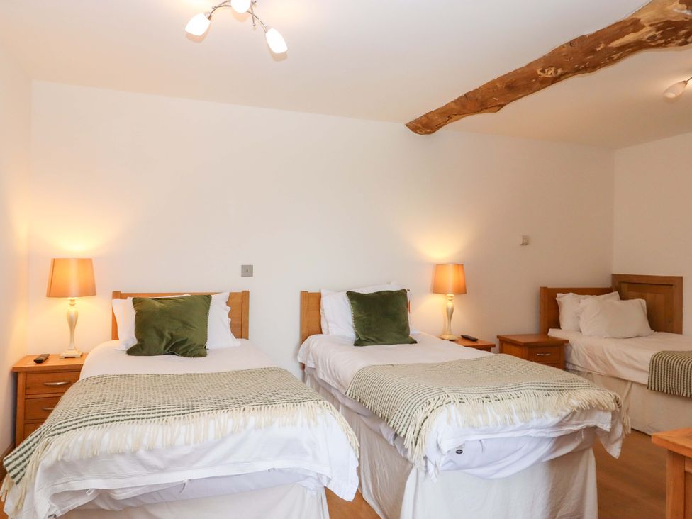 A bedroom with two single beds and a nightstand at Swallows Reach Halwell