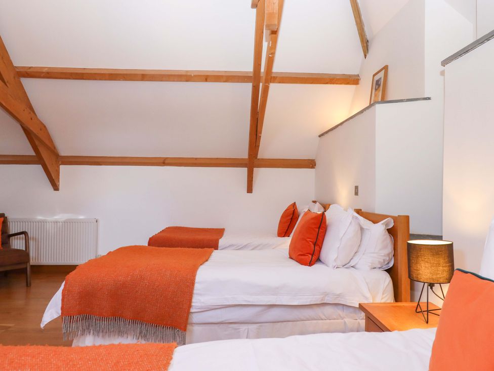 A bedroom with three beds and a chair at Swallows Reach in Halwell
