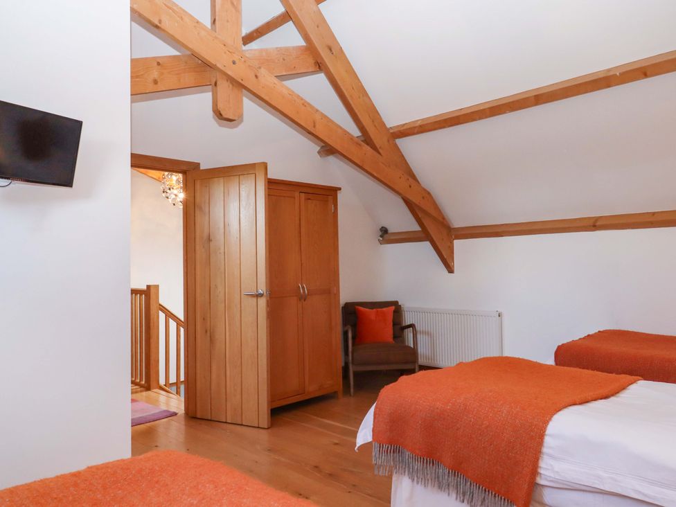 A bedroom with two beds and a wardrobe at Swallows Reach in Halwell