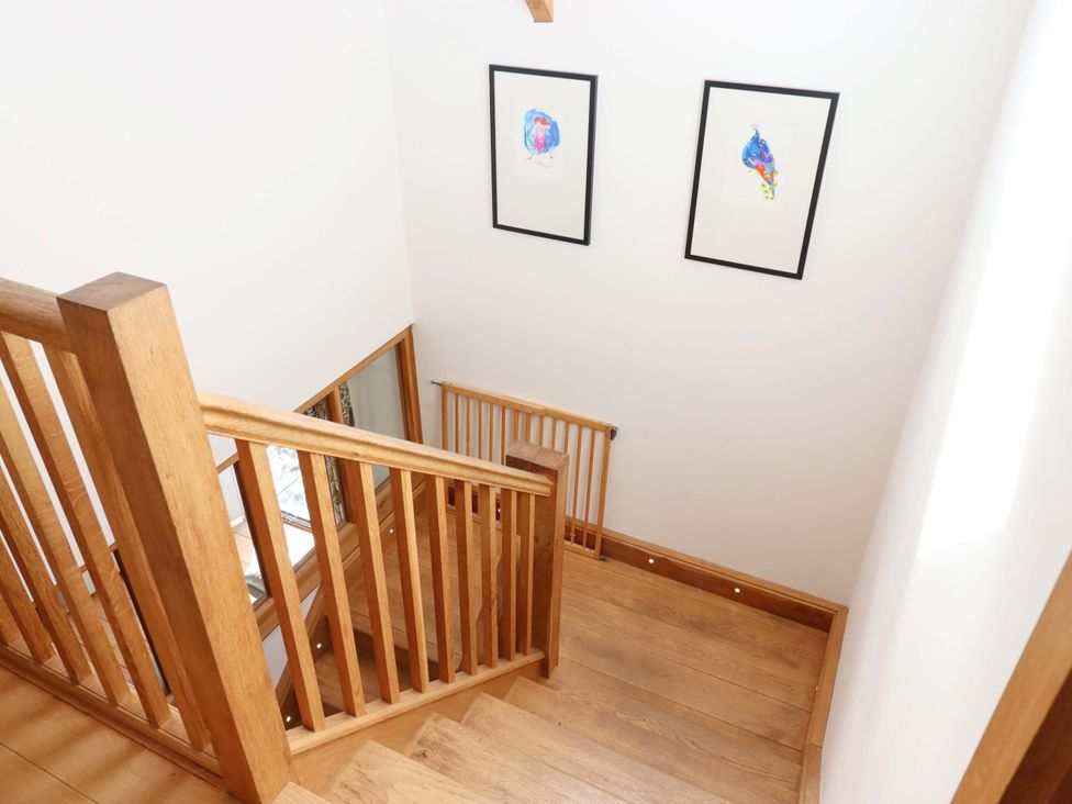 A staircase with wooden handrail and artwork at Swallows Reach Halwell