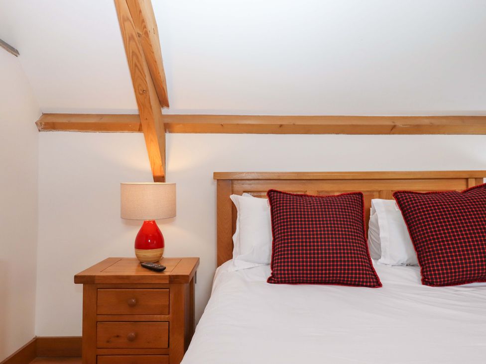 A bedroom with a bed and bedside table at Swallows Reach Halwell