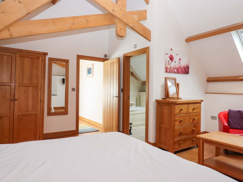A bedroom with wooden furniture and a mirror at Swallows Reach Halwell