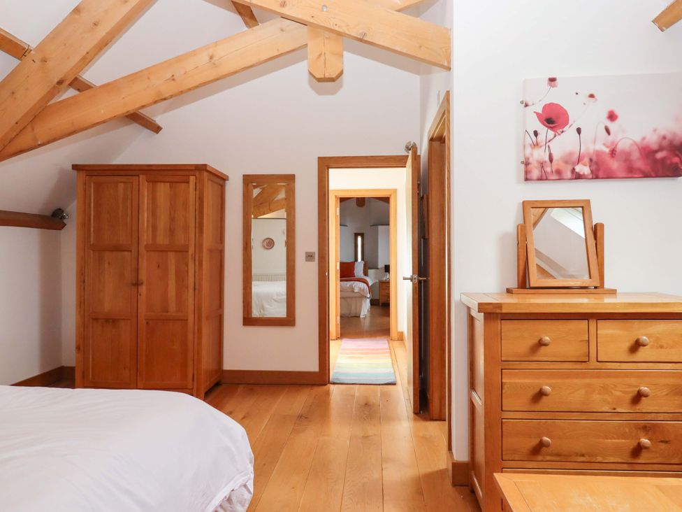A bedroom with wooden furniture and a doorway at Swallows Reach Halwell