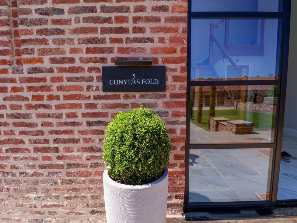 An outdoor view of a brick wall with a nameplate and a potted plant at Plot Four - Italian Terraced Garden Harpham near Nafferton