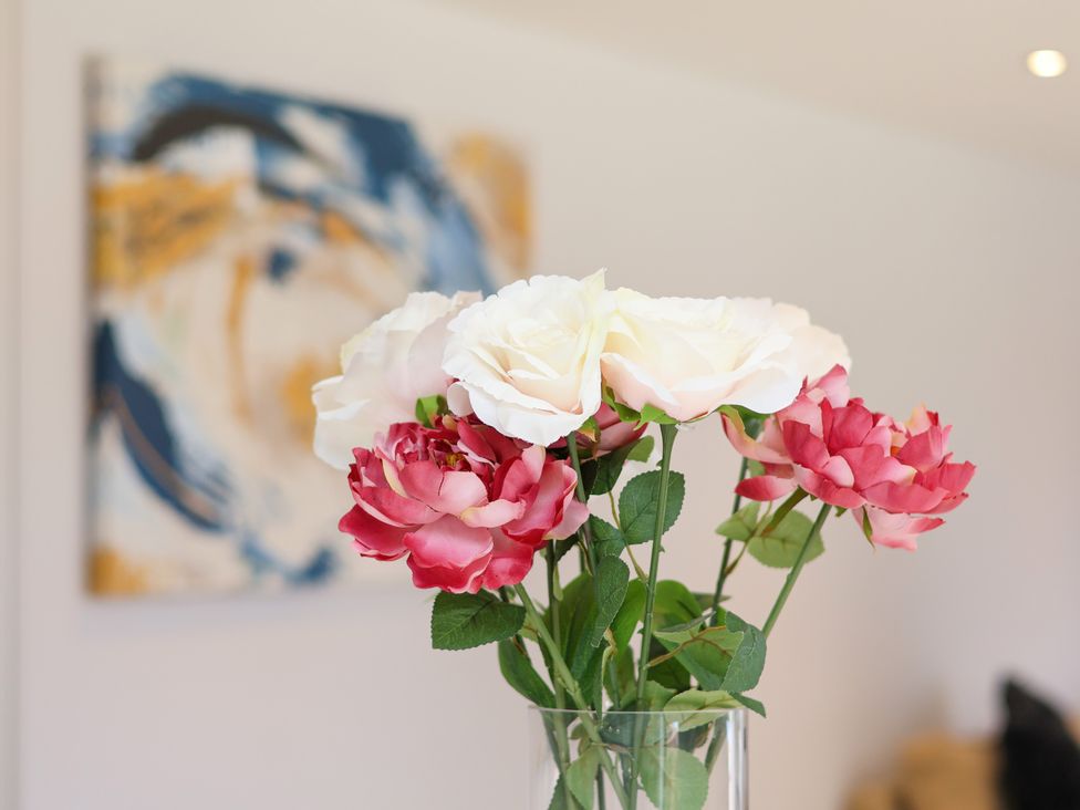 A vase with roses and artwork on the wall at Plot Four - Italian Terraced Garden in Harpham near Nafferton