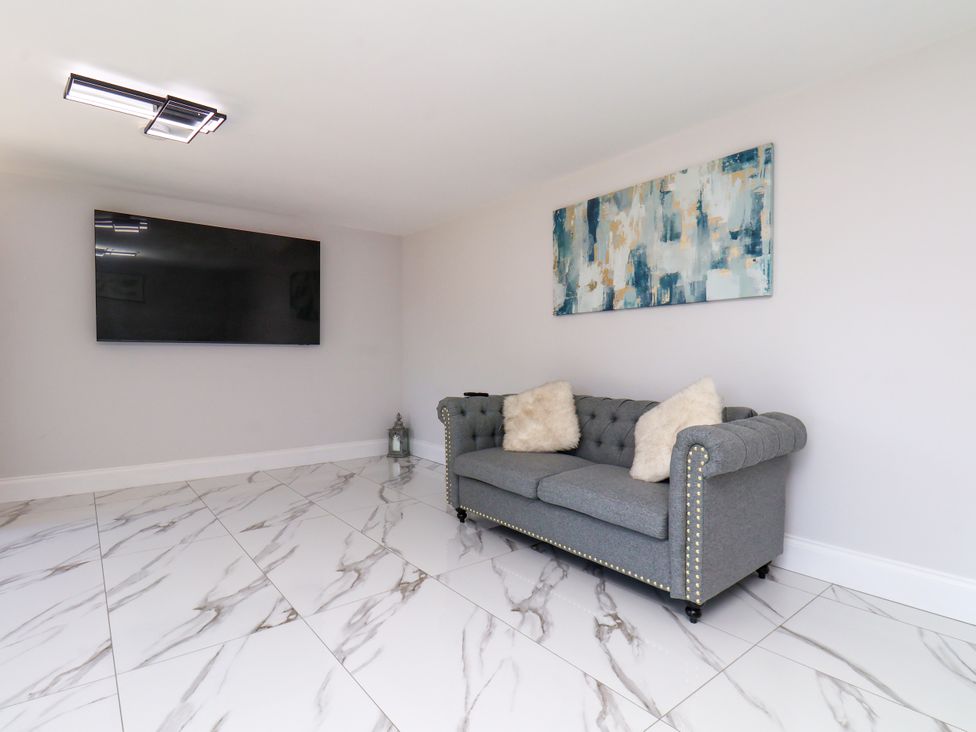 A living room with a grey sofa and television at Plot Four - Italian Terraced Garden Harpham near Nafferton