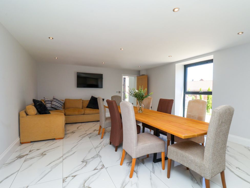 A dining room with a table and sofa at Plot Four - Italian Terraced Garden Harpham near Nafferton