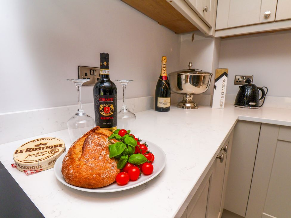 A kitchen counter with wine, bread, tomatoes and glasses at Plot Four - Italian Terraced Garden near Harpham