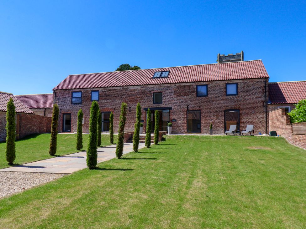 A garden with a building and pathway at Plot Four - Italian Terraced Garden in Harpham near Nafferton